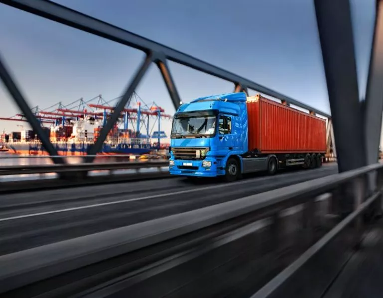 Ein LKW mit Container fährt über eine Hafenbrücke