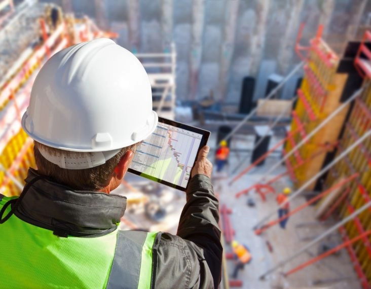 Baustellenlogistik-Arbeiter analysiert Projektstatus mit Tablet