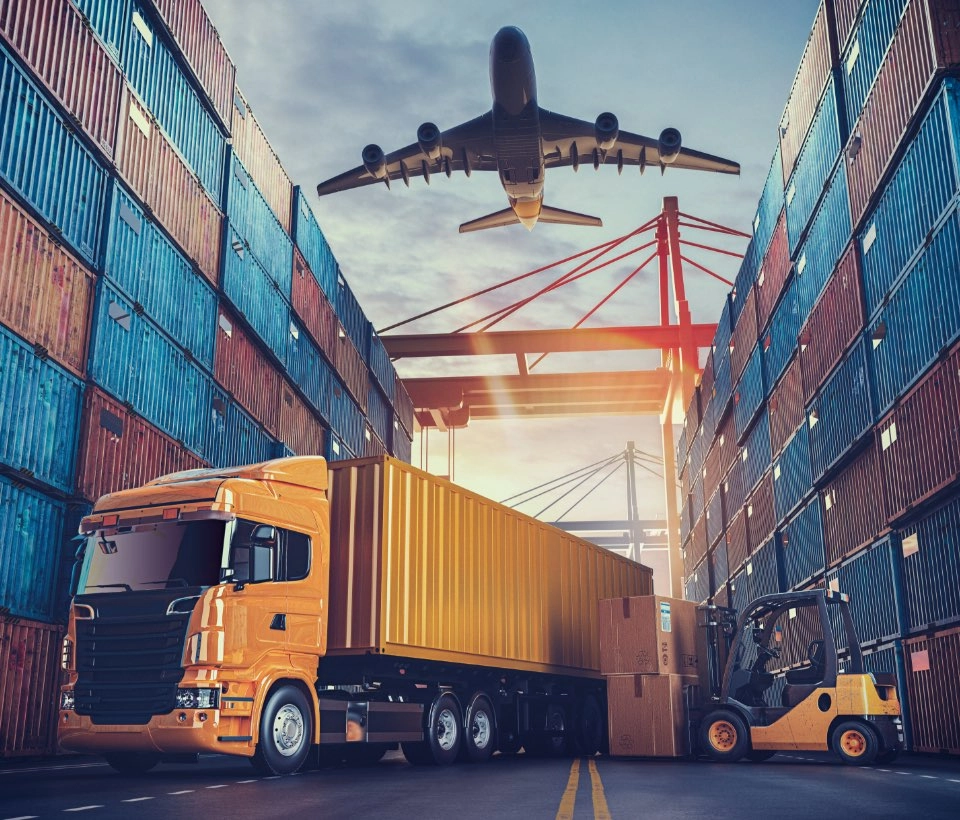 Ein Gabelstapler verlädt Kartons in einen gelben LKW im Hafen zwischen Containern, während über ihnen ein Flugzeug fliegt.