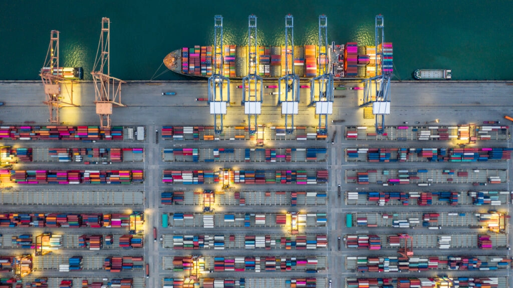 Aus der Perspektive von oben werden auf ein Containerschiff Container für den Transport im Rahmen der Transportorganisation geladen.
