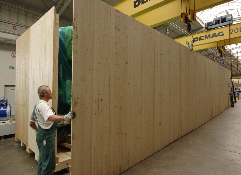 Ein Lagermitarbeiter verschließt die Seitenwände einer großen Holzverpackung.